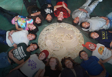 Students laying on the floor in a circle.